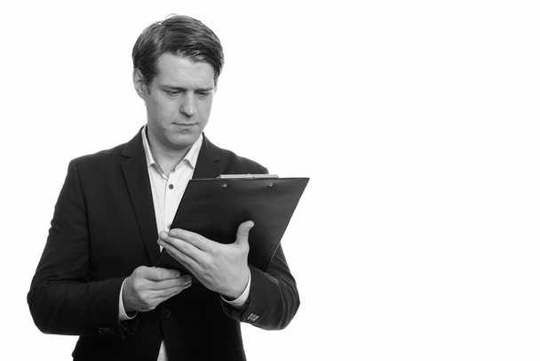 Studioaufnahme eines jungen, gut aussehenden skandinavischen Geschäftsmannes im Anzug isoliert vor weißem Hintergrund in schwarz-weiß - Foto, Bild