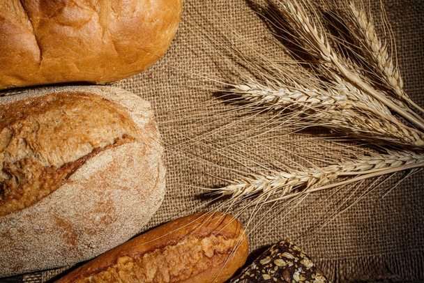 Diversi pani di pane saporito con grano, farina e glutine su un tavolo di legno
 - Foto, immagini