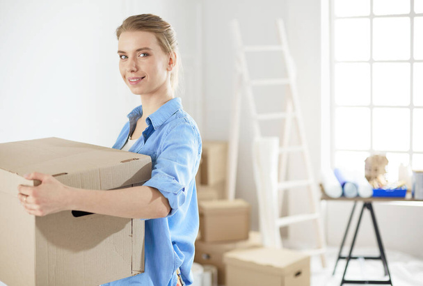 Young woman moving house to new home holding cardboard boxes - Foto, afbeelding