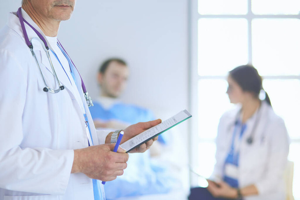 Doctor holding folder in front of a patient and a doctor - Foto, imagen
