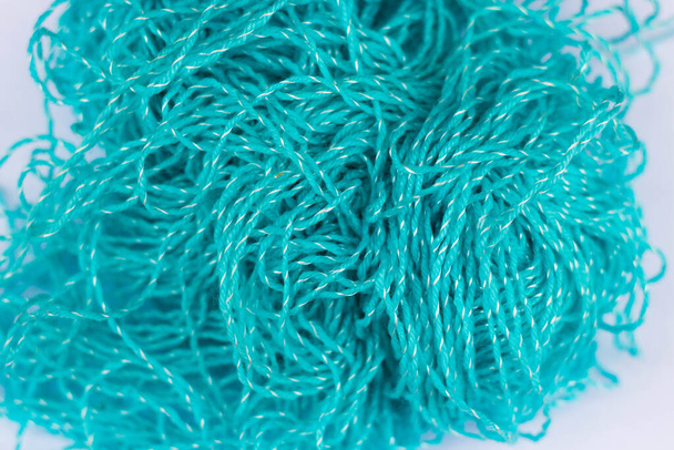 A kötési téma háttere. Egy gombolyag kusza kék akril fonal fehér alapon közelről középen fókuszálva és elmosódva a széleken - Fotó, kép