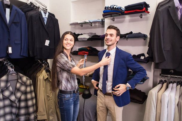 Girl seller helps to pick up a client in a tie menswear boutique - 写真・画像