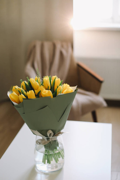 Flowers in living room interior. Bouquet of fresh tulips on table. Birthday or holiday, Easter concept. Minimal festive home decor - Photo, image