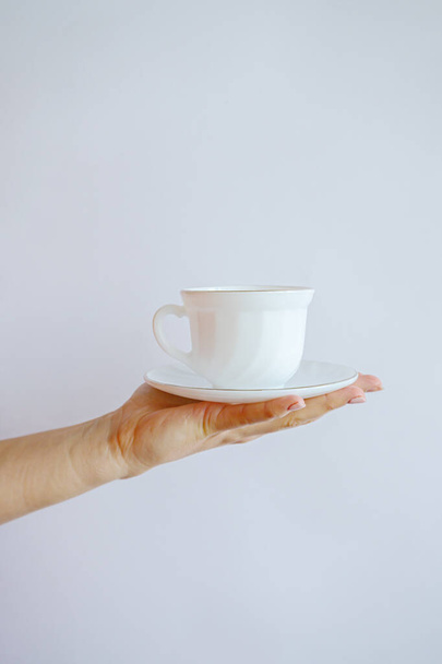 white mug with a cup in hand on a white wall background - Fotó, kép