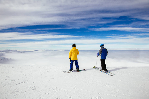 Лыжники смотрят на красивый снежный пейзаж с вершины горы. На заднем плане Высокие Татры. Пик Чопок, Низкие Татры, Словакия, Европа
. - Фото, изображение