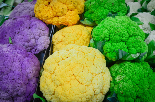 Farbenfrohe Sammlung weißer, grüner, gelber und lila Blumenkohlköpfe auf dem Bauernmarkt in Puyallup, Washington, Amerika. Vollformat gesunde Gemüseauslage am Lebensmittelstand - Foto, Bild