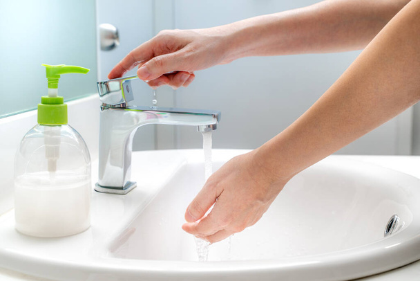 Woman washing her hands with soap at the sink for good hygiene and to prevent covid-19 virus - 写真・画像