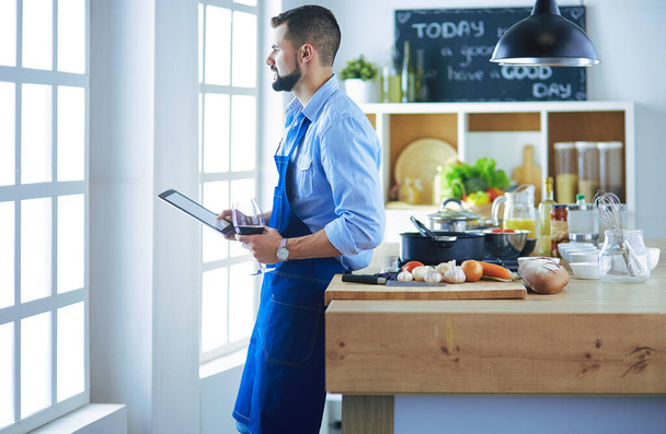 Man following recipe on digital tablet και το μαγείρεμα νόστιμο και υγιεινό φαγητό στην κουζίνα στο σπίτι - Φωτογραφία, εικόνα