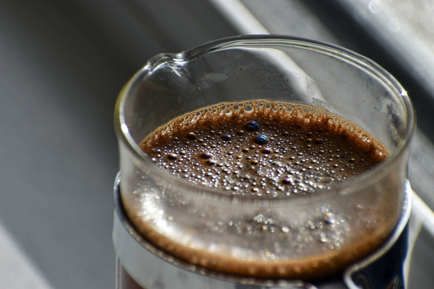 A close up of a cafetiere brewing coffee on a kitchen window ledge - Photo, Image