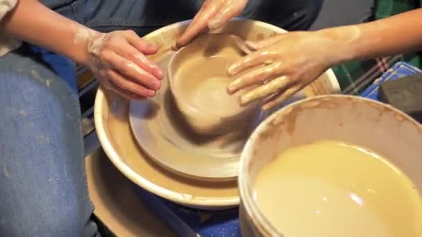 Woman and boy make plate on pottery wheel in workshop - Footage, Video