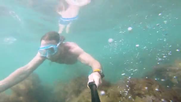 Egy maszkos izomember úszik a víz alatt, kamerát tartva maga előtt. Közelkép. - Felvétel, videó