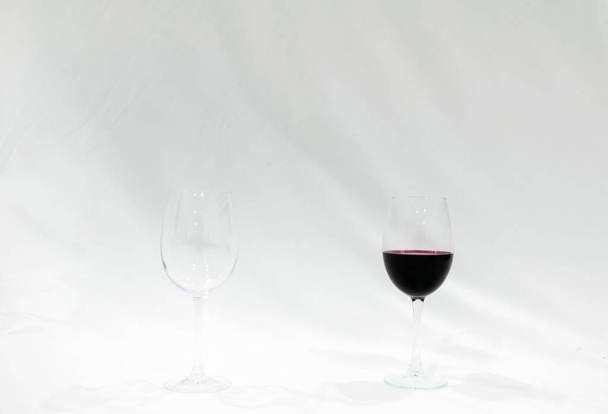 leeg glas wijn met rood glas wijn dat zowel op het pallete met witte achtergrond staat. Creatieve lege ruimte afbeelding. - Foto, afbeelding