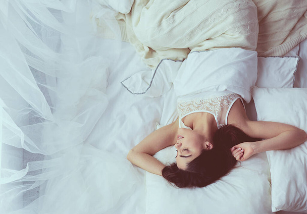 Pretty woman lying down on her bed at home - Фото, зображення