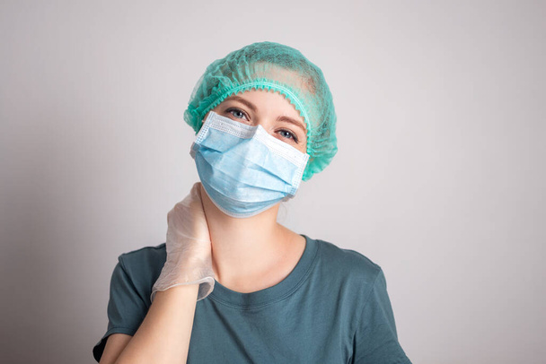 Jonge blanke vrouw arts verpleegkundige in chirurgische masker ziet er moe - Foto, afbeelding