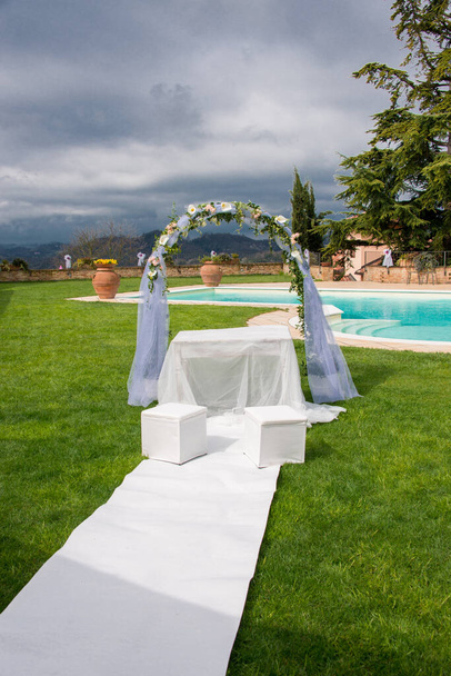 hermoso arco de boda en el jardín con un césped blanco  - Foto, imagen