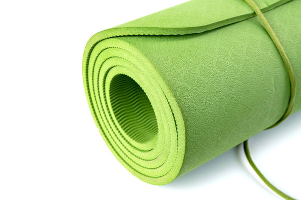 Зеленый свернутый спальный коврик изолирован на белом фоне. Спортивное оборудование
 - Фото, изображение