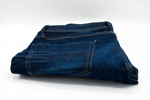 Um par de jeans skinny azul dobrado em um fundo branco
 - Foto, Imagem
