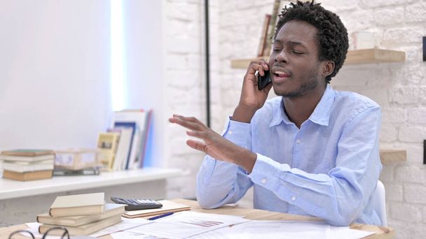 Kiireinen Afrikkalainen mies puhuu puhelimessa
 - Valokuva, kuva
