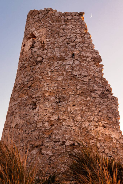 Vartiotorni auringonlaskun aikaan kultaisella valolla ja kuulla, joka sijaitsee Cala Agullan ja Cala Mesquidan välissä, Mallorca, Espanja
 - Valokuva, kuva