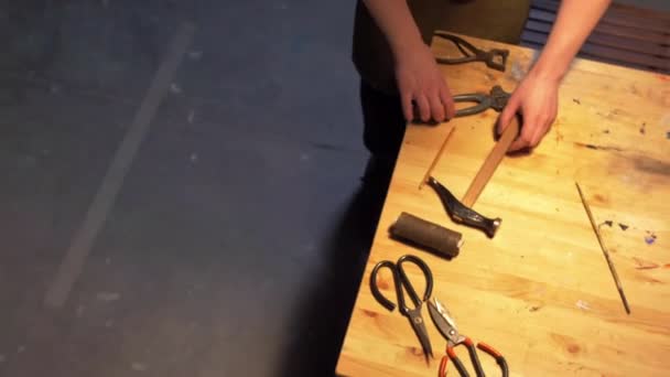 Az ember munkaeszközöket készít az asztalon egy műhelyben - Felvétel, videó