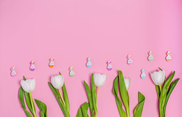 Boeket witte tulpen en decoratieve wasknijpers op een roze achtergrond, kopieerruimte, vlakke lay - Foto, afbeelding
