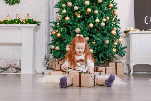 happy girl opening Christmas presents at home - Foto, imagen