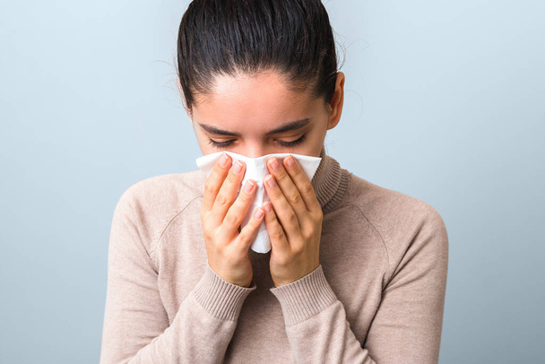 stop spreading coronavirus. young sick woman with fly or virus sneezing and coughing in a mask or napkin looking very hopeless. - Fotoğraf, Görsel