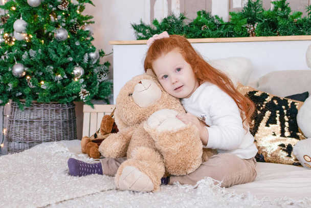 μικρό κορίτσι αγκαλιά αρκούδα τα Χριστούγεννα - Φωτογραφία, εικόνα