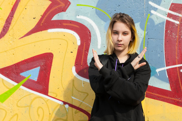 Adolescente chica de pie delante de la pared de color y mostrar el signo de parada coronavirus
 - Foto, imagen