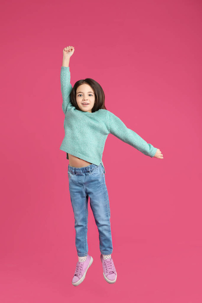 Cute little girl jumping on pink background - Fotoğraf, Görsel