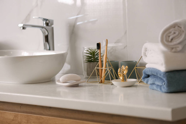 Toiletries and stylish vessel sink on light countertop in modern bathroom - Foto, afbeelding