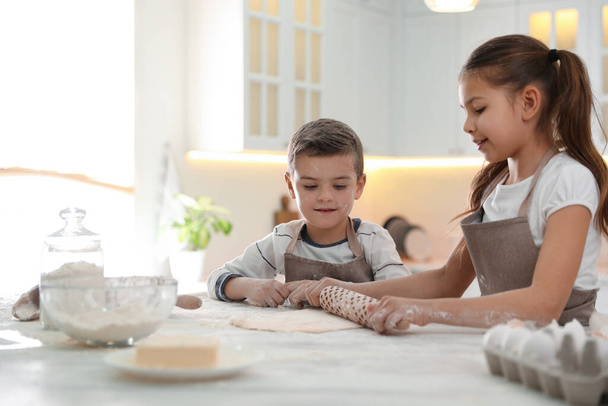 Cute little children cooking dough together in kitchen - Photo, image