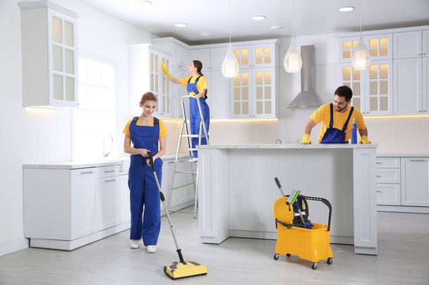 Team of professional janitors cleaning modern kitchen - Foto, imagen
