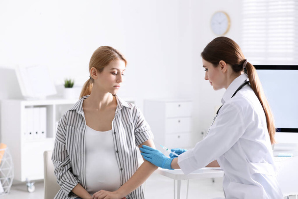 Lääkäri antaa ruiskeen raskaana olevalle naiselle sairaalassa. Rokotuskäsite
 - Valokuva, kuva
