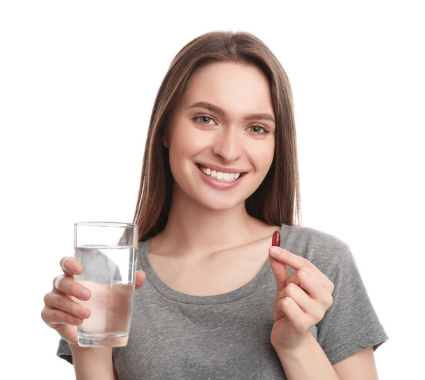 Young woman with vitamin pill and glass of water on white background - Valokuva, kuva
