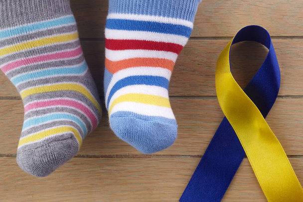 World Down syndrome day background. Down syndrome awareness concept. Socks and ribbon on wooden background - Foto, afbeelding