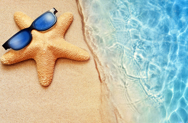 Summer sand beach background. Starfish in sunglasses and sea. Summer concept. - Fotografie, Obrázek
