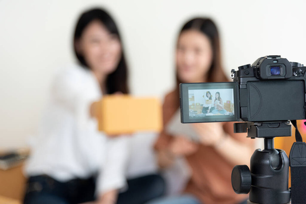 Nahaufnahme einer digitalen Videokamera, die zwei Mädchen aufzeichnet, die neue Produktwerbung präsentieren. Vlog und Influencer-Konzept. Menschen in Teilzeit und Beruf. Junge Teenager mit moderner Technik - Foto, Bild