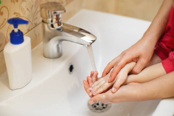 Mamá con un hijo se lava las manos de un coronavirus. Higiene para lavarse las manos de gérmenes y virus
 - Foto, Imagen