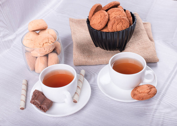 Two cups of tea with biscuit and chocolate - 写真・画像