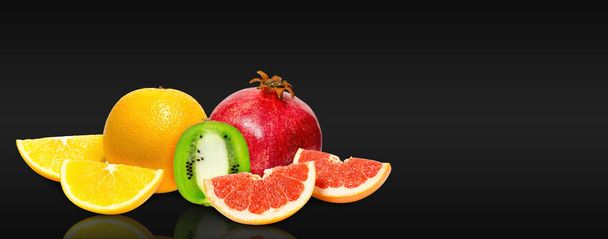 Fresh and ripe fruits, orange, kiwi, grapefruit and pomegranate on black background. Natural vitamins. Copy space. - Photo, Image