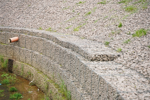 el borde del arroyo de la ciudad, hecho de piedras en una rejilla de hierro. Nadie.
 - Foto, Imagen