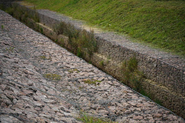el borde del arroyo de la ciudad, hecho de piedras en una rejilla de hierro. Nadie.
 - Foto, Imagen