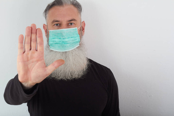 Retrato de hombre barbudo de mediana edad con máscara médica. Un concepto del peligro del coronavirus para los ancianos
. - Foto, Imagen