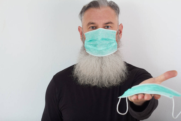 医療マスクの中年髭男の肖像画。高齢者のためのコロナウイルスの危険性の概念. - 写真・画像