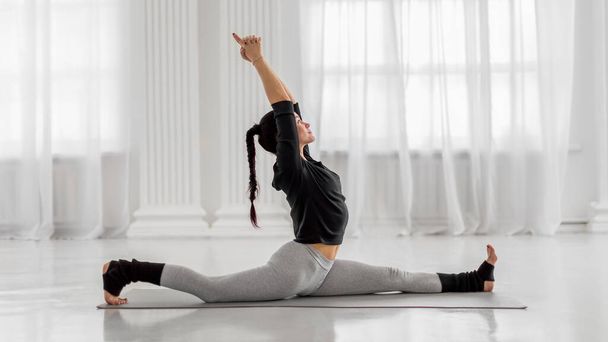 Atraktivní mladá asijská žena cvičit přední splits nebo Monkey Pose na šedé podložce. Hanumanasana - Fotografie, Obrázek
