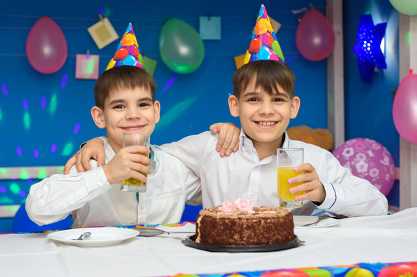 Dos chicos comen pastel y beben jugo en una fiesta de cumpleaños
 - Foto, imagen