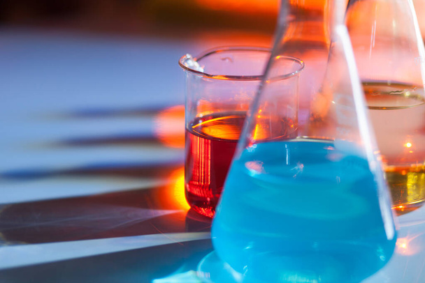 Frasco de laboratorio iluminado archivado con soluciones químicas de colores con sombras sobre la mesa. Laboratorio, ciencia, química... consepto. - Foto, Imagen
