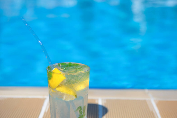 Fresh Mojito Cocktail at the edge of the resorts pool in summer. Luxury vacation concept, a place for text - Φωτογραφία, εικόνα