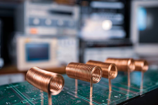 Close-up of high-frequency copper wire on green microcircuit on background of numerous blurry computers. Concept production of super modern high-tech components for transceiver appliances - Photo, image